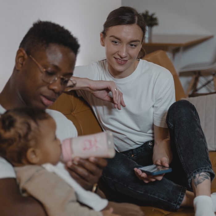 Family feeding baby from a bottle on the couch