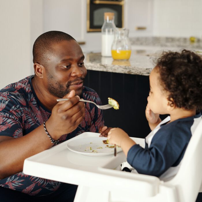 Man feeding child in highchair