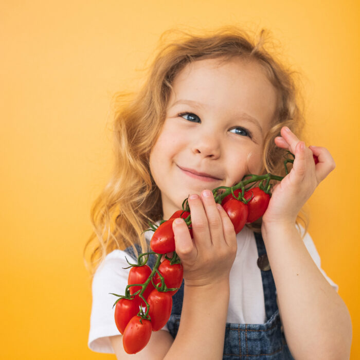 Kid holding a cluster of tomatoes