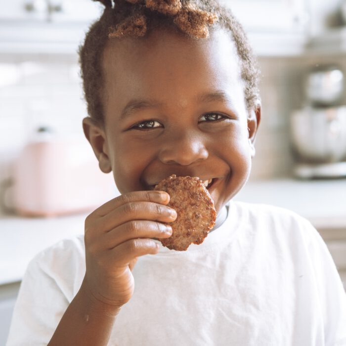 Smiling kid eating a sausage patty